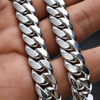 A close-up of a polished silver Cuban link chain draped across a person's hand.