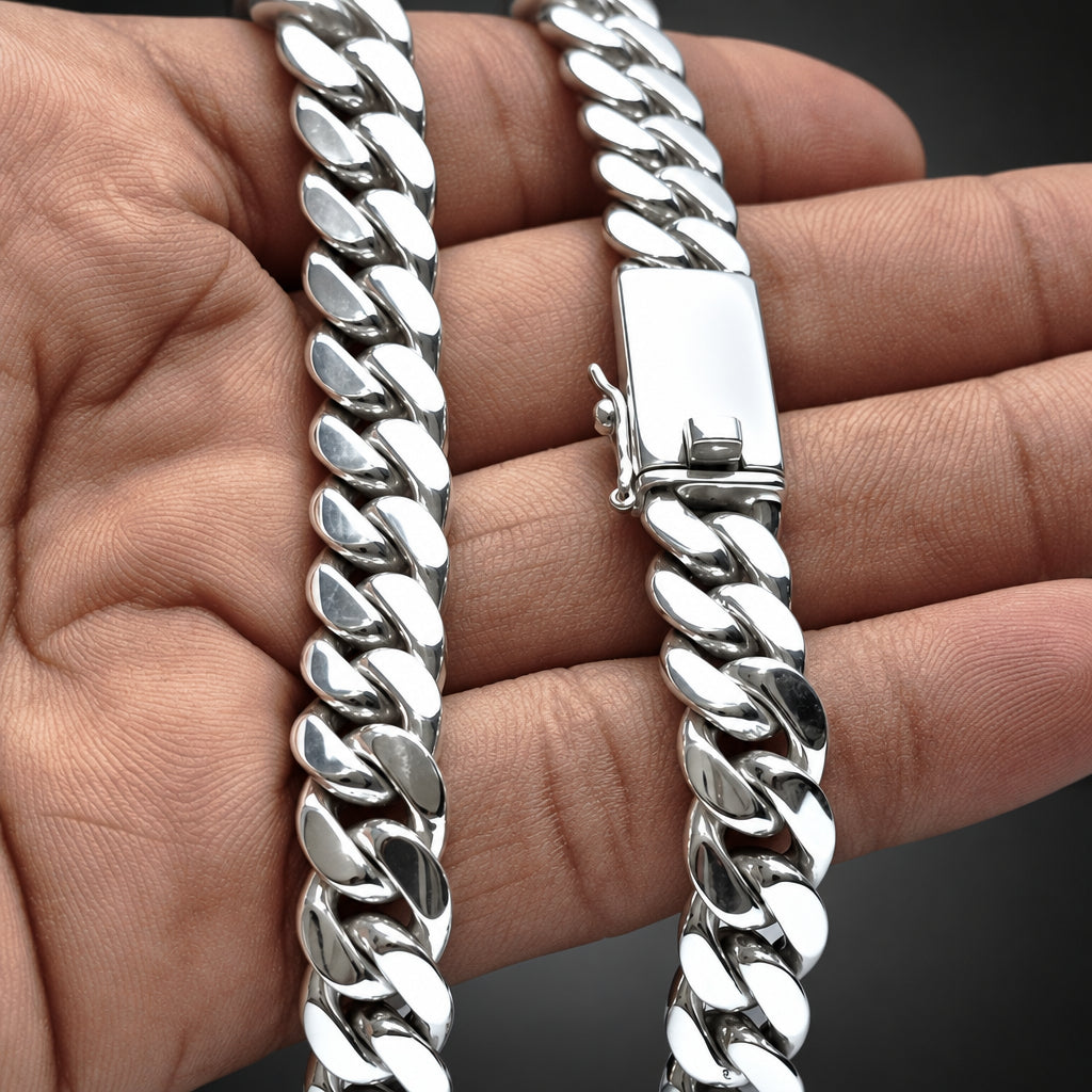 A close-up of a silver Cuban link chain bracelet being held in a person's hand, showing the polished metal links and clasp.