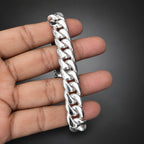 Silver chain bracelet held in a hand against a dark background