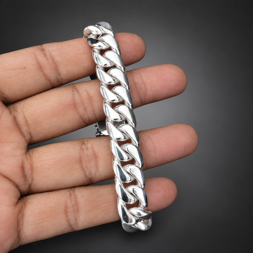 Silver chain bracelet held in a hand against a dark background