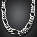 A polished silver-tone Cuban link chain necklace displayed on a light brown wooden surface.