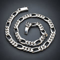 A silver-toned metal chain necklace with a curb link pattern, coiled on a plain white background.