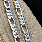 Close-up of two silver chain necklaces on a wooden surface