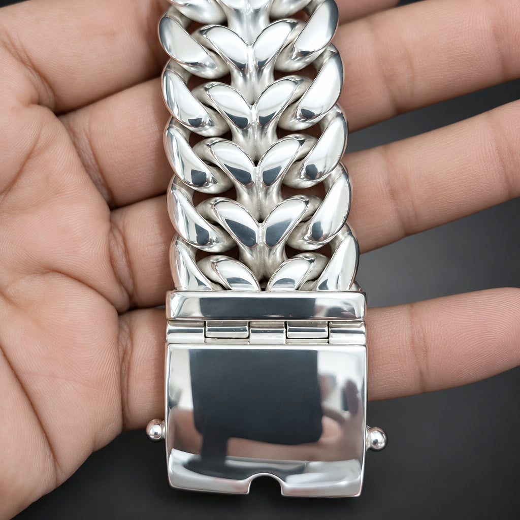 Silver bracelet with leaf-like design held in a hand