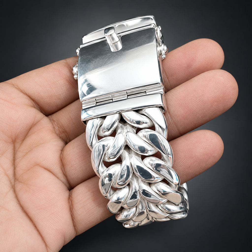 Silver bracelet with intricate design held in a hand against a dark background