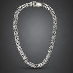 A silver-toned Russian link chain necklace with a polished clasp, displayed in a neat loop against a dark gray gradient background.