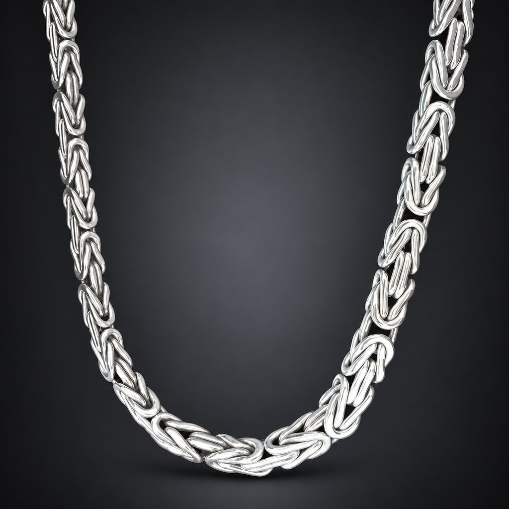 A silver-toned braided chain necklace with a polished finish, arranged in a U-shape against a dark gray gradient background.