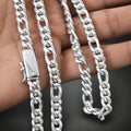 Two silver chains on a hand with a dark background