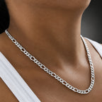 Silver chain necklace worn by a person with a blurred background