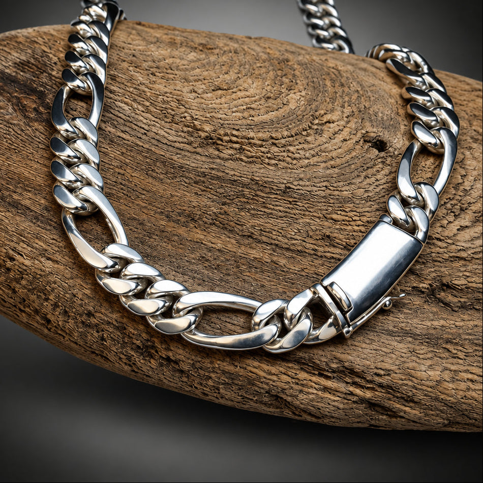A silver-toned chunky curb chain necklace with a polished rectangular clasp, draped over a textured brown wooden log against a dark gray gradient background.