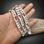 Two gold chain bracelets on a hand with a dark background