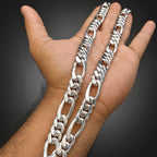 Silver chain necklace on a hand against a black background