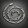 A polished silver-tone metal chain necklace with a curb-style link pattern, coiled on a dark gray gradient background.