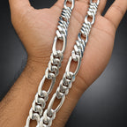 Silver chain necklace held in a hand against a dark background