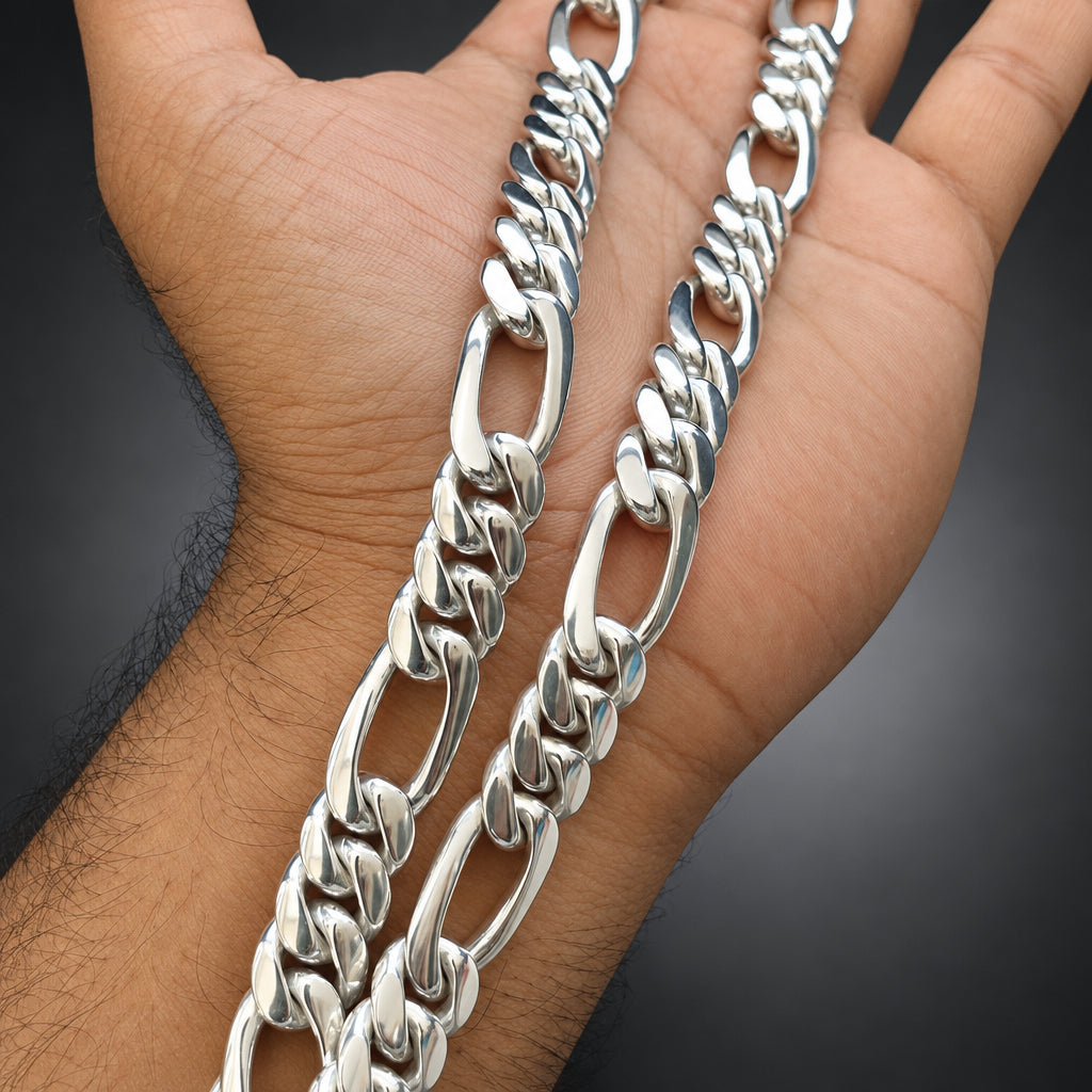 Silver chain necklace held in a hand against a dark background