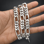 Three silver chain bracelets on a hand against a black background