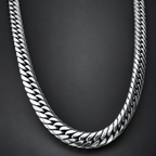 A close-up of a polished silver-tone Cuban link chain necklace arranged in a U-shape against a dark gray background.