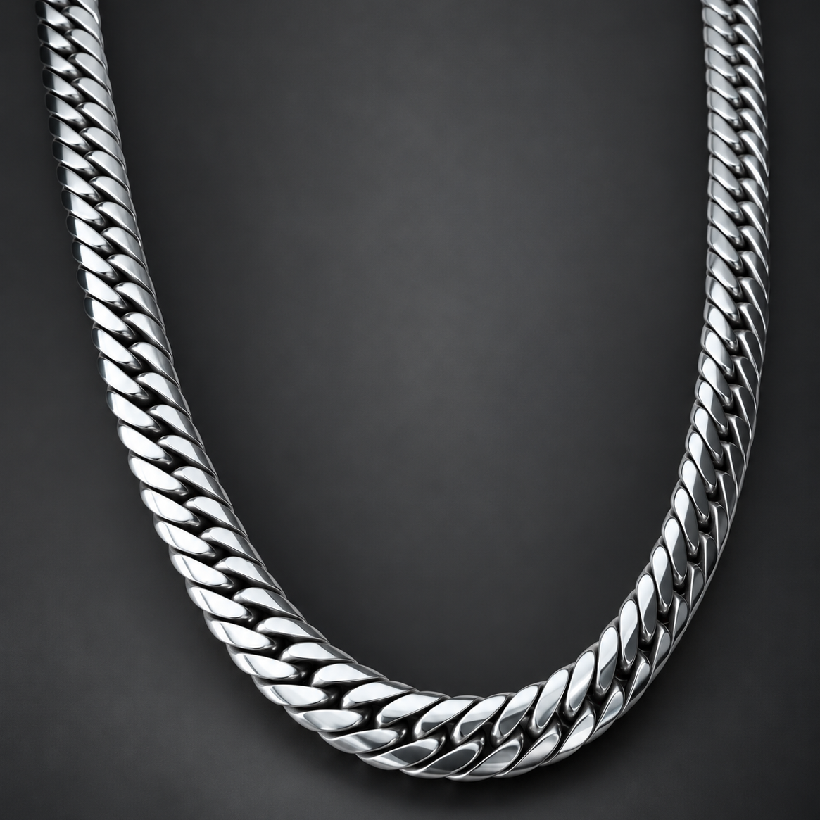 A close-up of a polished silver-tone Cuban link chain necklace arranged in a U-shape against a dark gray background.