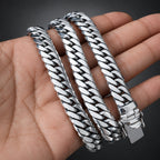 Three silver braided bracelets on a hand with a dark background