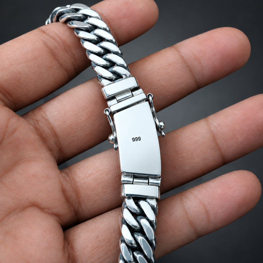 Silver bracelet with a clasp held in a hand against a dark background