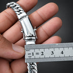 Silver bracelet being held with a ruler for measurement