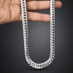 Silver chain held by a hand on a dark background