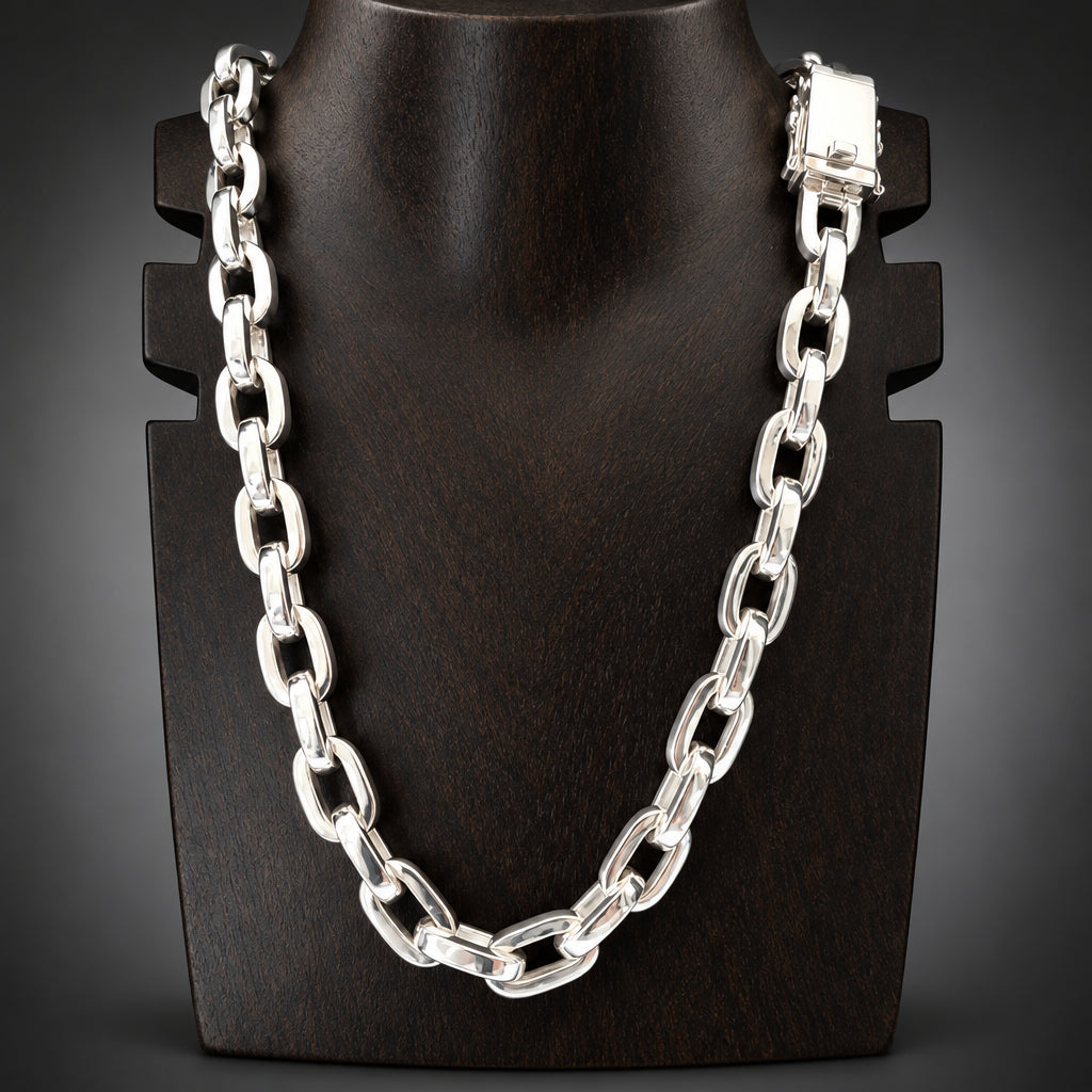 A polished silver-tone metal link chain necklace displayed on a black mannequin bust against a dark gray background.
