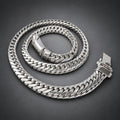A thick silver Cuban link chain necklace coiled on a dark gray gradient background.