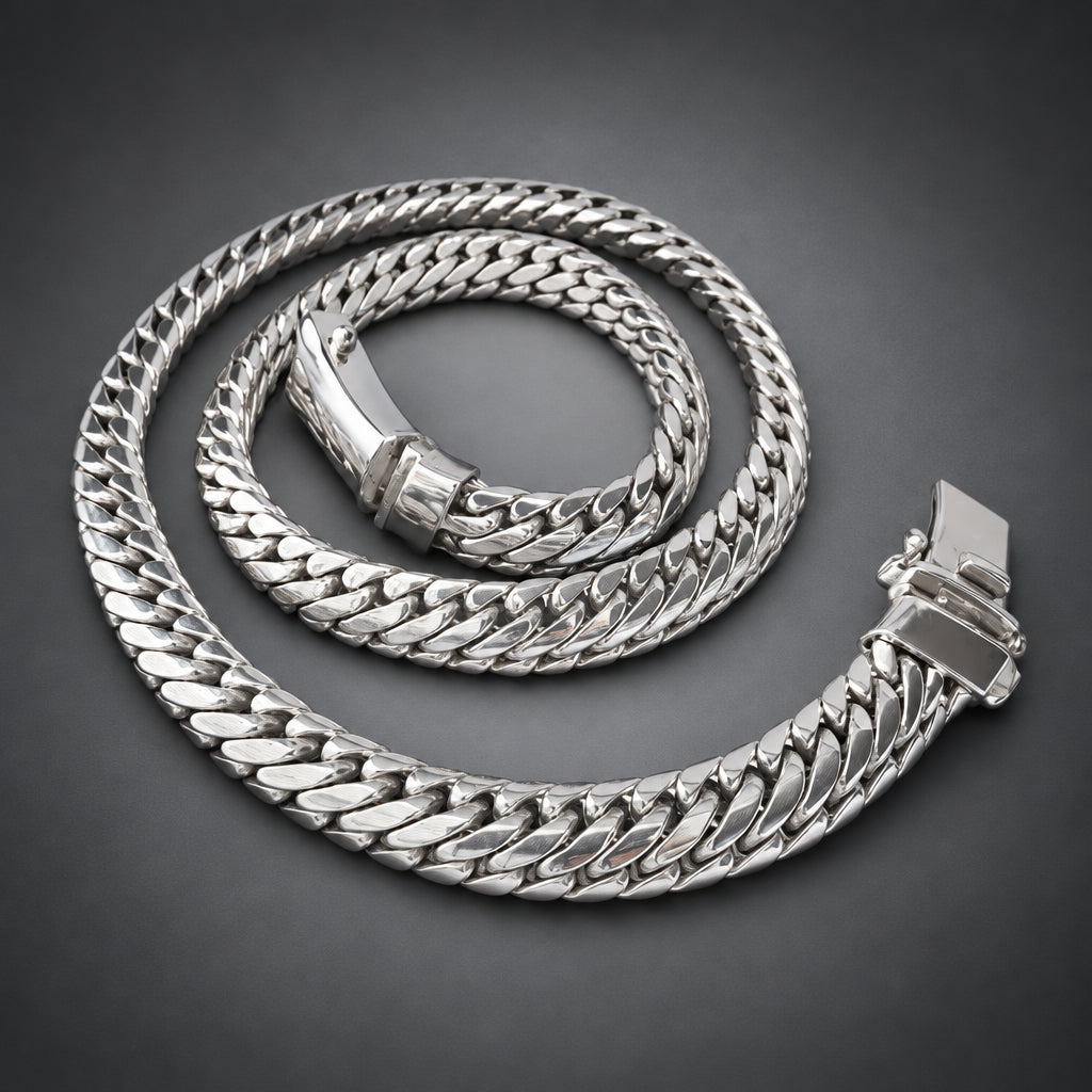 A thick silver Cuban link chain necklace coiled on a dark gray gradient background.
