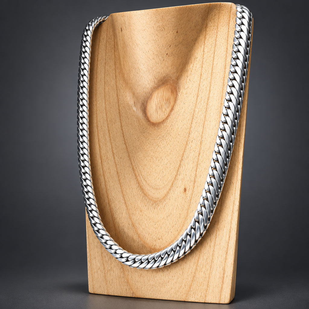A thick silver Cuban link chain necklace displayed on a light wood neck stand against a dark gray studio background.