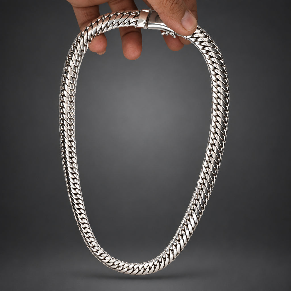 Silver chain necklace held by a hand on a dark gray background