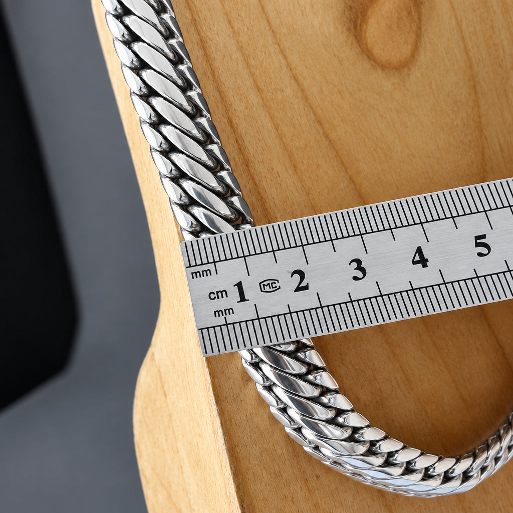 Silver chain on a wooden surface with a ruler for scale