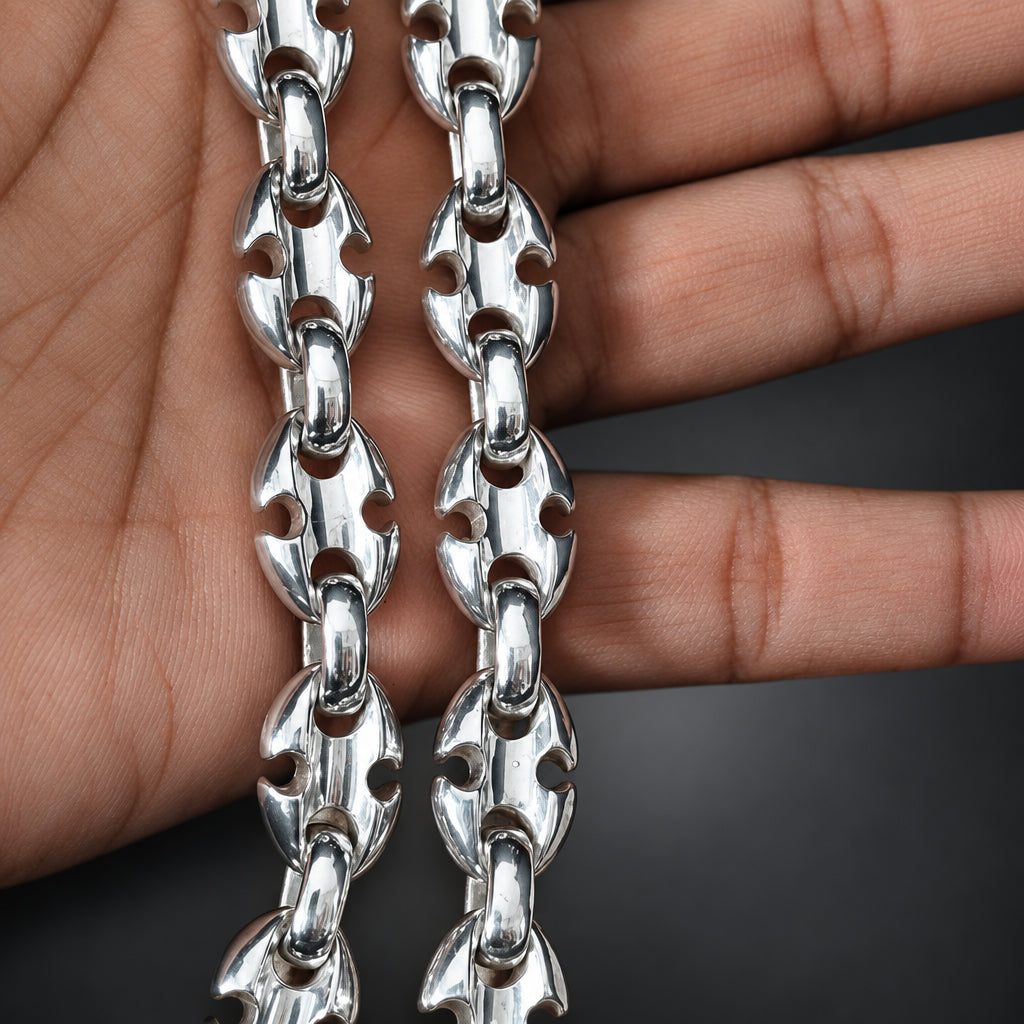 Silver chain held between fingers on a dark background