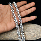 Silver chain held by a hand on a wooden surface