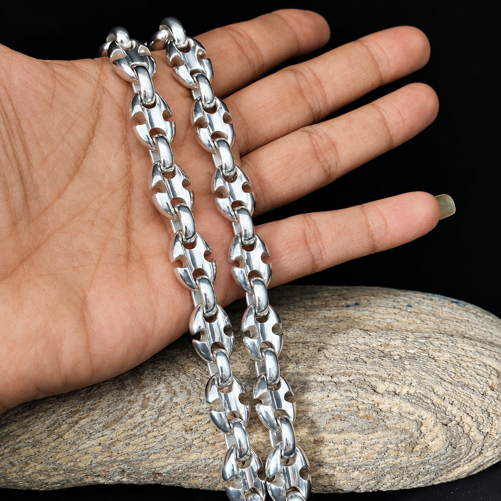 Silver chain held by a hand on a wooden surface