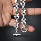Silver chain bracelet held by a hand on a gradient dark background