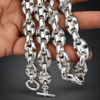 Silver chain necklace held by a hand against a gradient dark background