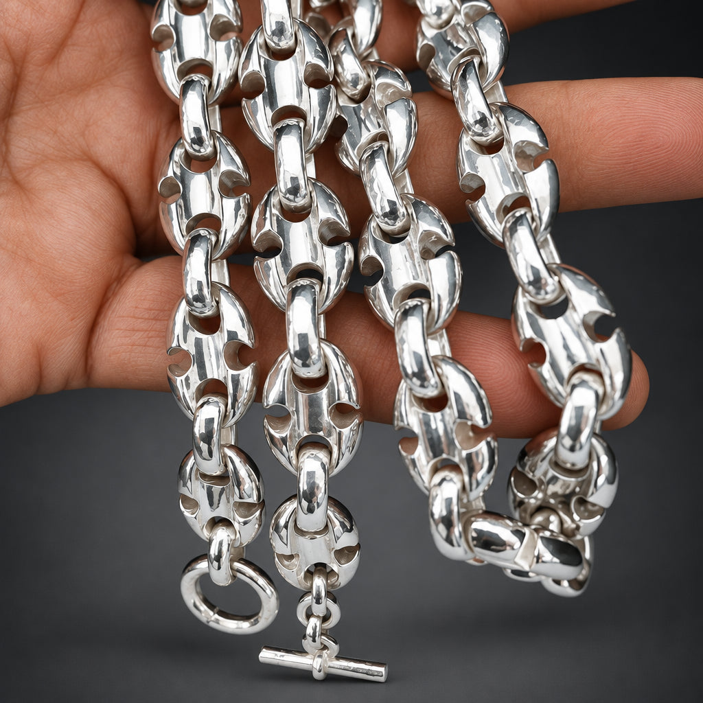 Silver chain necklace held by a hand against a gradient dark background