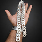 Hand holding a large white chain necklace against a dark background