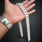 Hand holding a large white chain against a dark background
