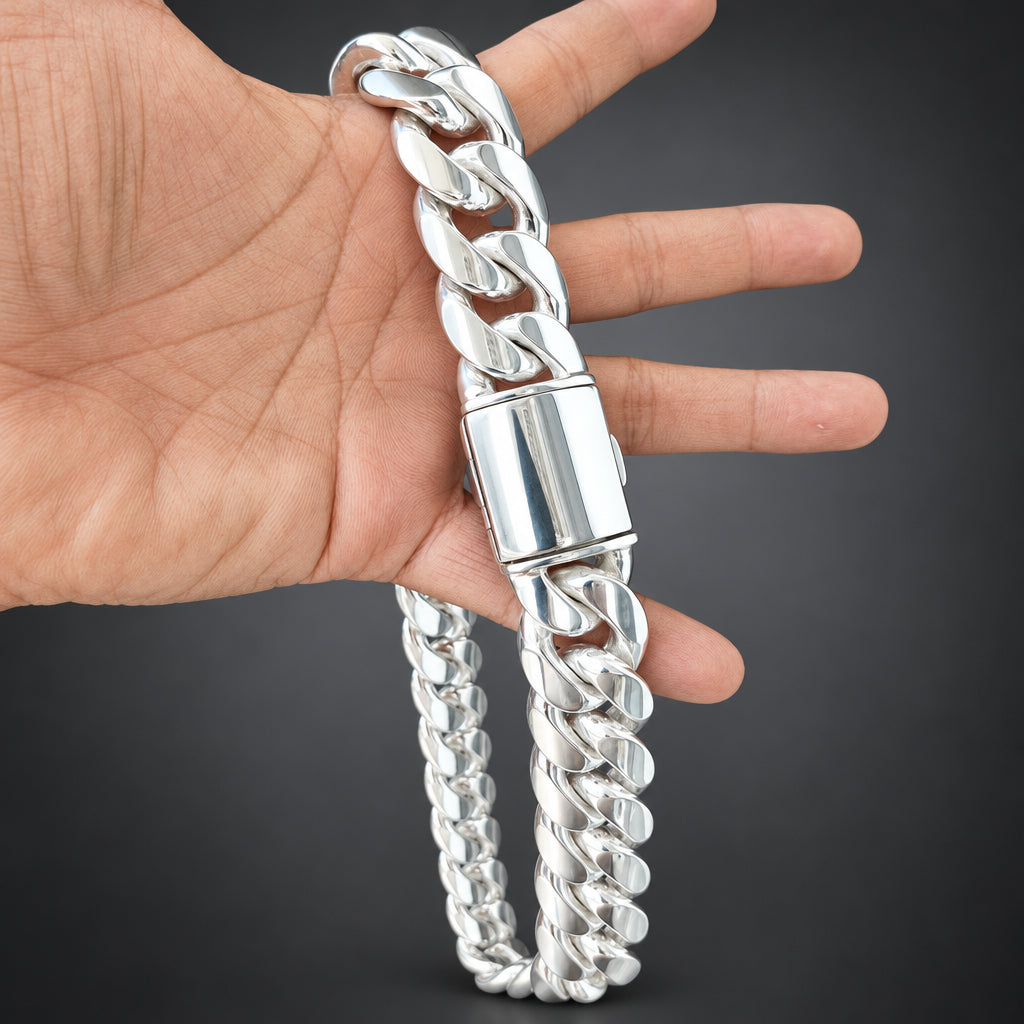 Silver chain bracelet being held by a hand on a dark surface