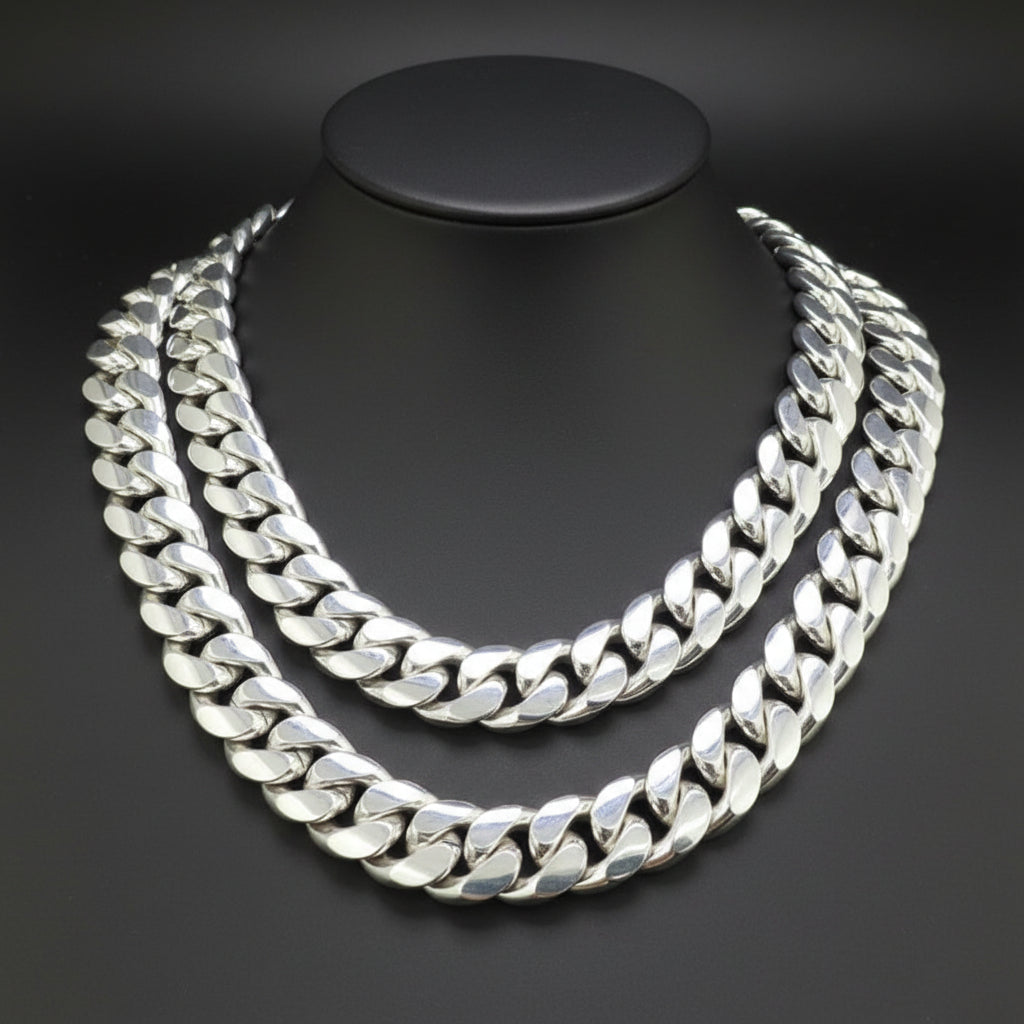 A thick silver Cuban link chain necklace displayed on a black mannequin bust against a dark gray background.