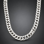A polished silver Cuban link chain necklace arranged in a U-shape against a dark gray gradient background.