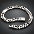 A silver-toned Cuban link chain bracelet with a polished rectangular clasp, displayed on a dark reflective surface.