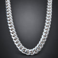 A chunky silver Cuban link chain necklace displayed on a light wood mannequin neck.