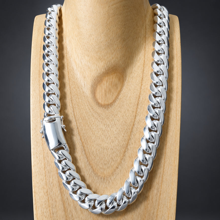 A thick silver Cuban link chain necklace displayed on a light wood neck stand against a dark gray background.