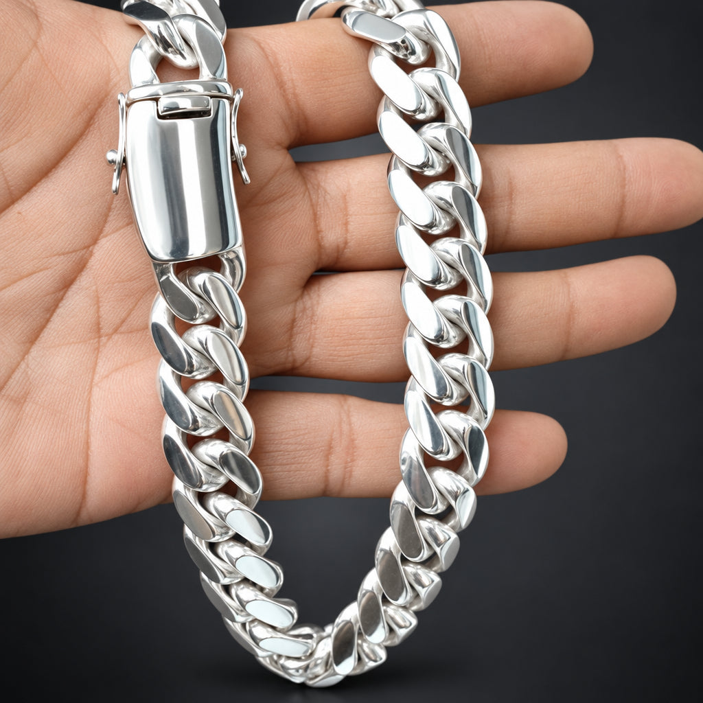 A polished silver Cuban link chain necklace draped over a person's hand against a dark background.