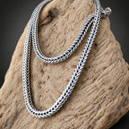 Silver braided necklace on a stone surface