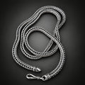 Silver braided necklace on a hand against a dark background