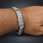 Silver bracelet with intricate design on a wrist against a dark background